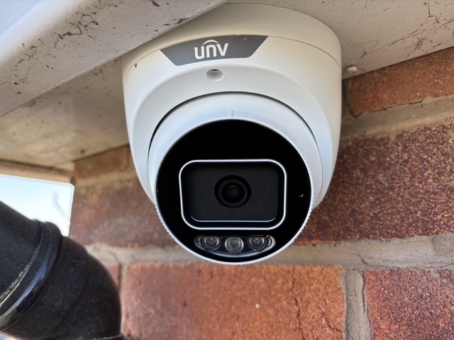 White CCTV camera fitted under the eaves